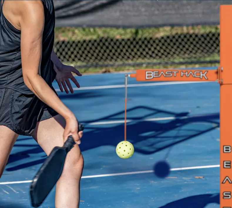 Pickleball player training with Beast Hack ball-on-string trainer on blue court